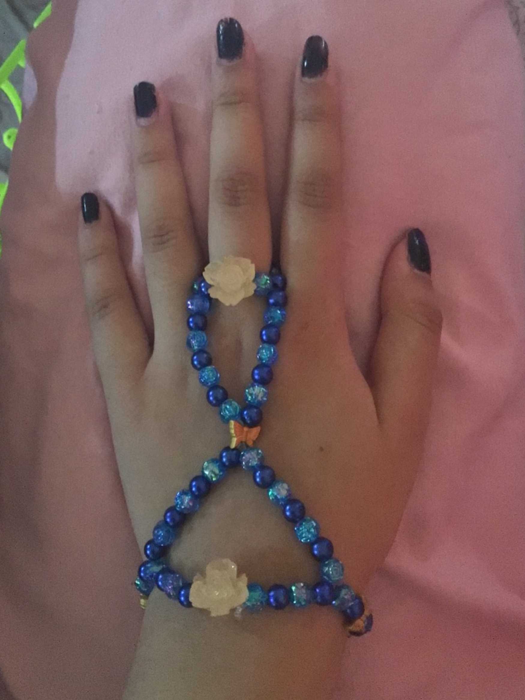 A alternating dark and light blue beads kandi single and ring connected to eachother, with the occasional rose and butterfly.